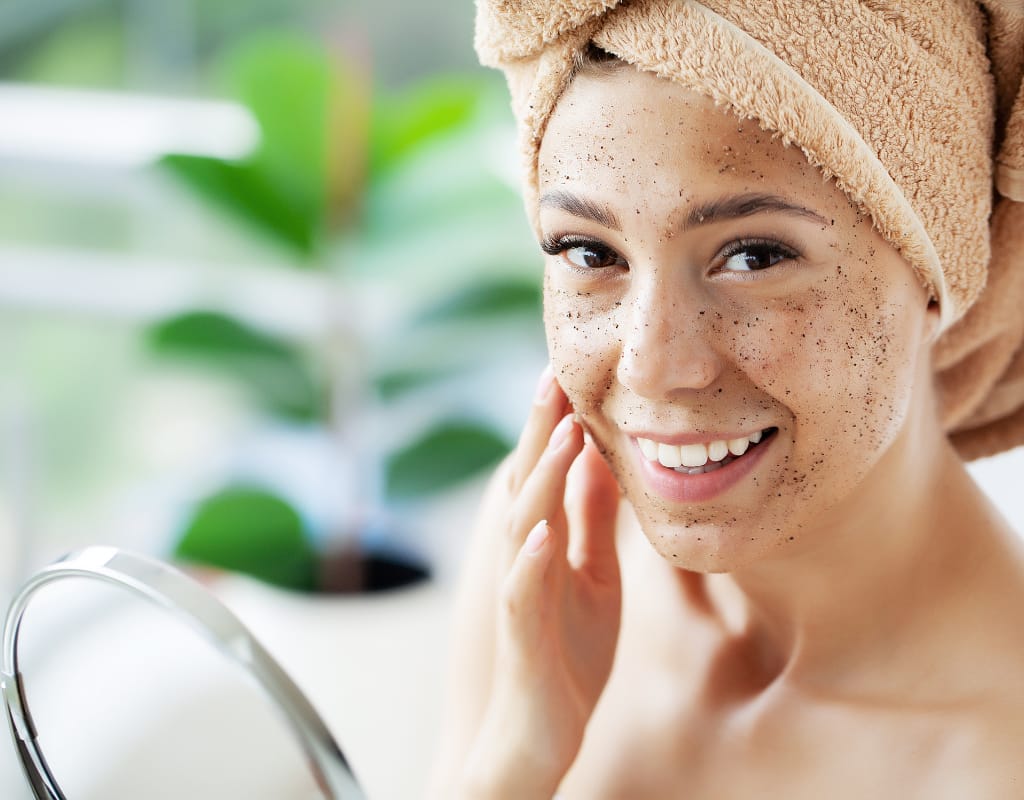 woman with towel on her head exfoliating her facial skin