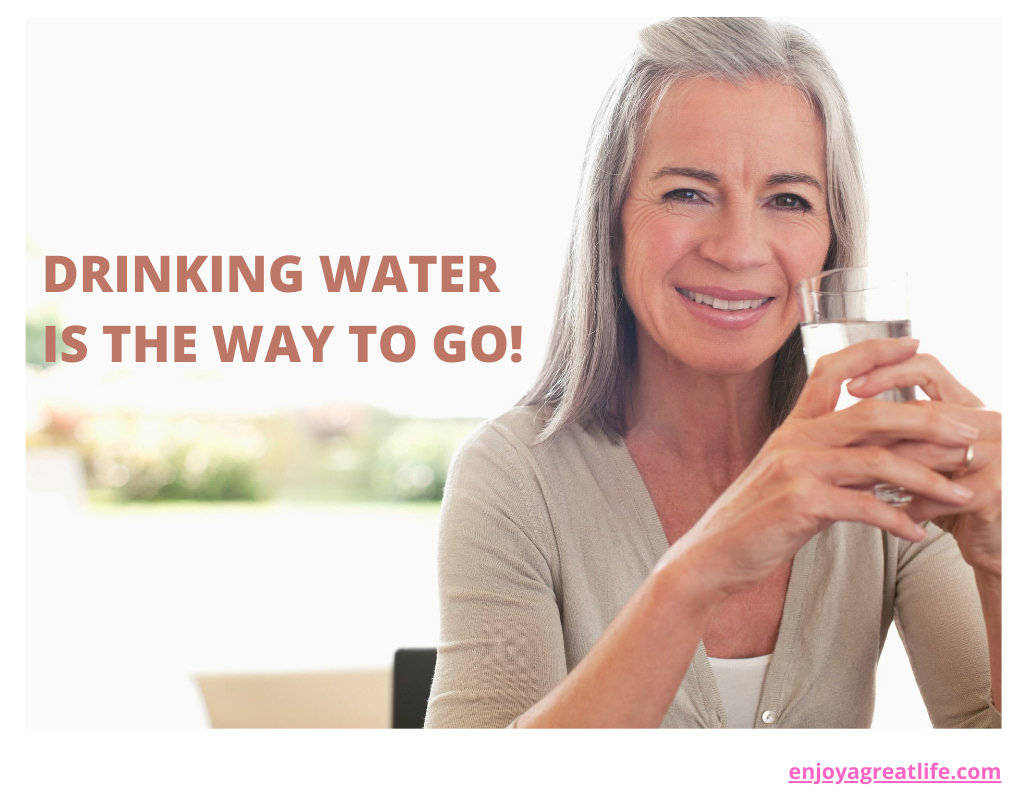 woman glass of water in her hand - quote drinking water is the way to go