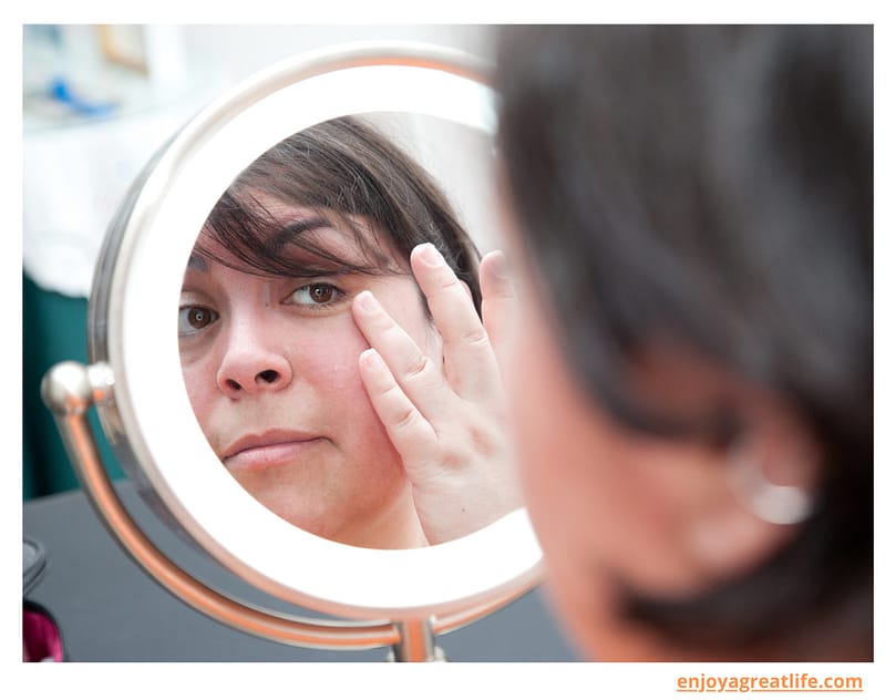 woman looking at herself in mirror skin problems on face