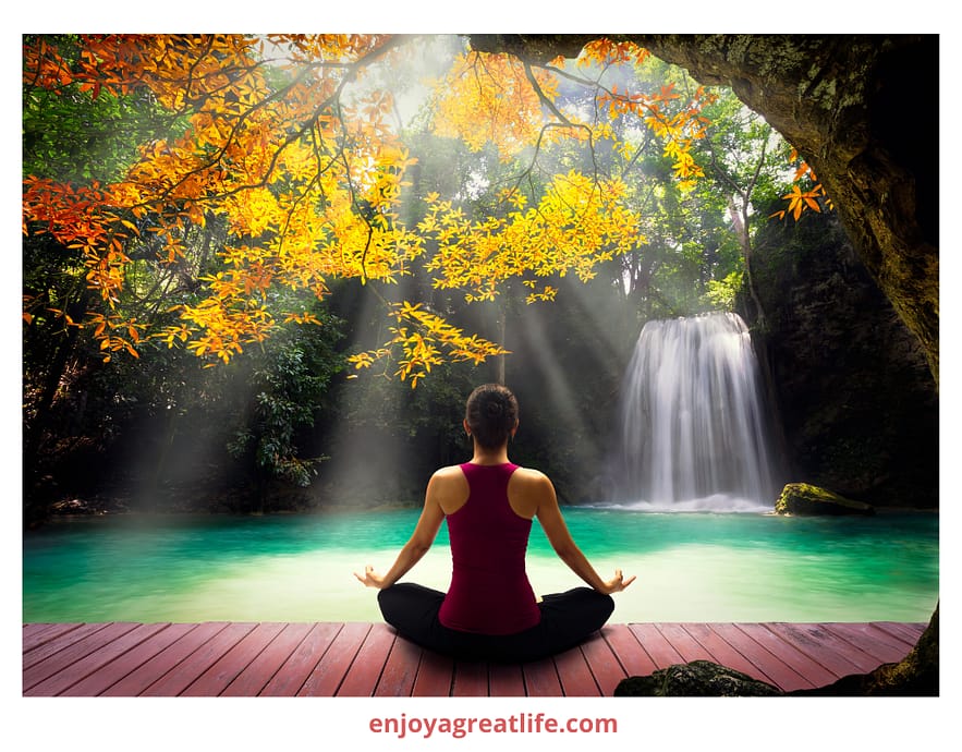 woman meditating beautiful scenery in front of a waterfall